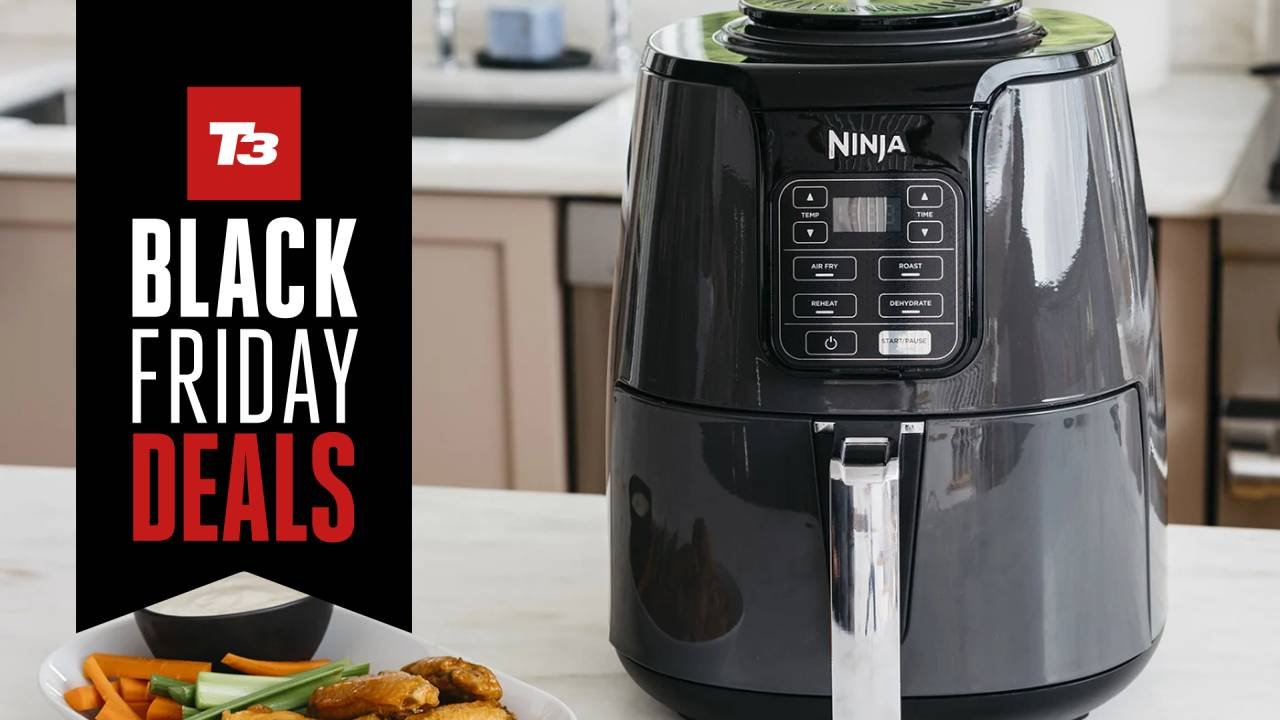 Black air fryer on a kitchen counter with potatoes and towels