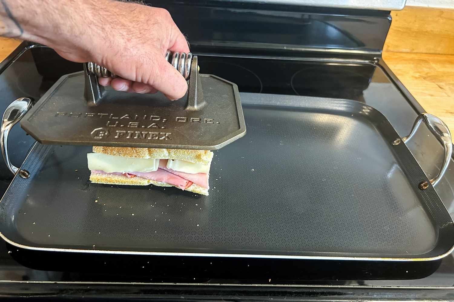 Cast iron burger press cooking a patty on a griddle