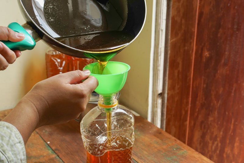 Clear oil funnel beside a glass bottle of cooking oil on a kitchen counter