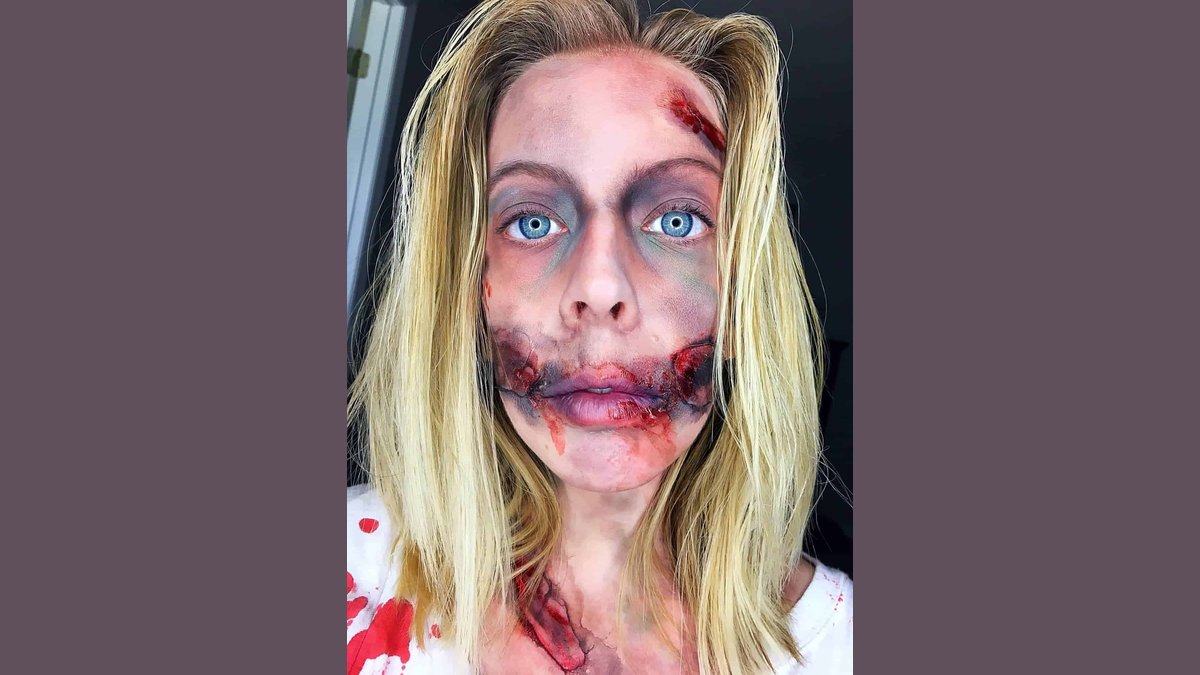 A close-up of realistic Halloween zombie makeup featuring textured wounds and pale, weathered skin.