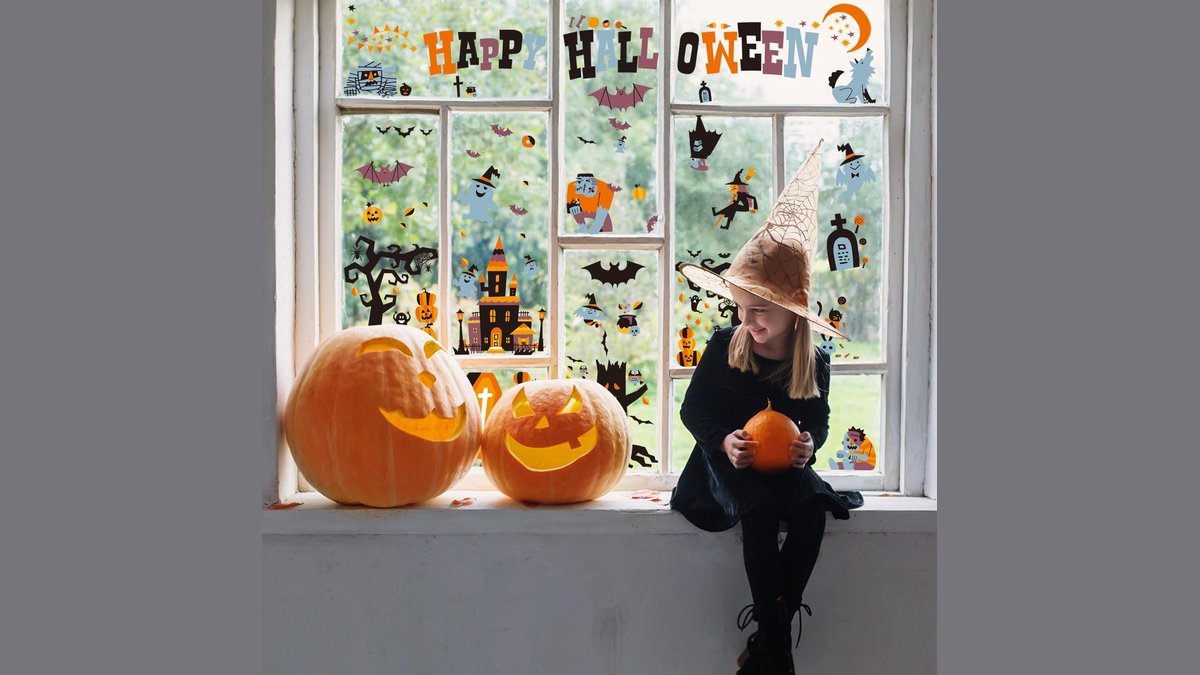 Colorful halloween window clings shaped like bats and pumpkins on a glass window.