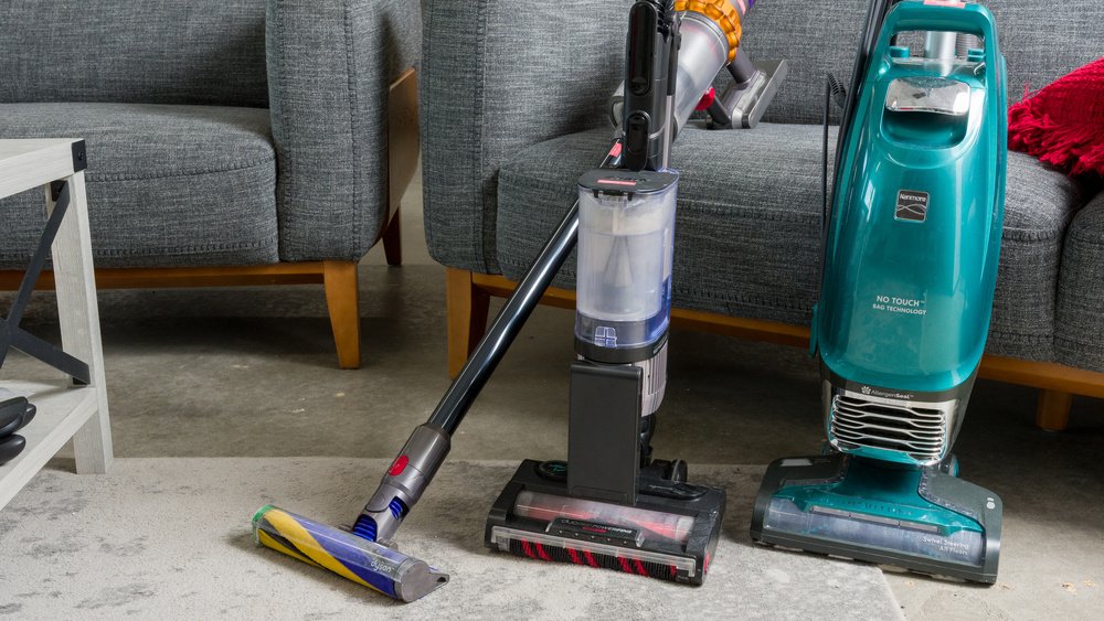 Compact canister vacuum cleaner on light oak floor in a bright apartment living room