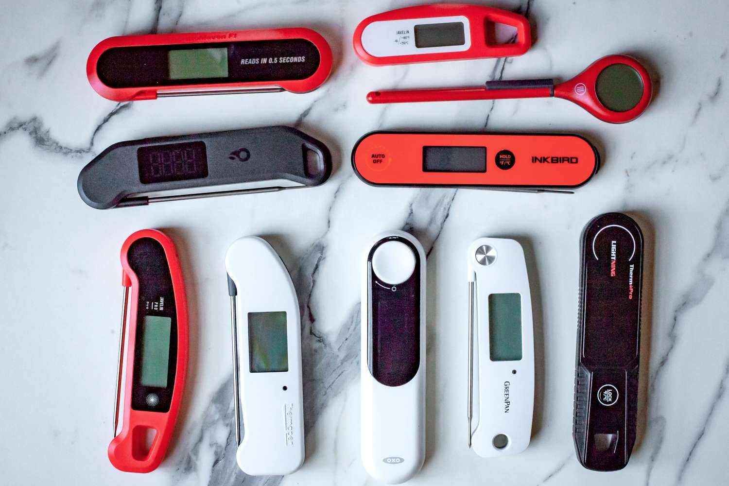 Digital instant-read meat thermometer probe on a marble countertop in a modern kitchen.