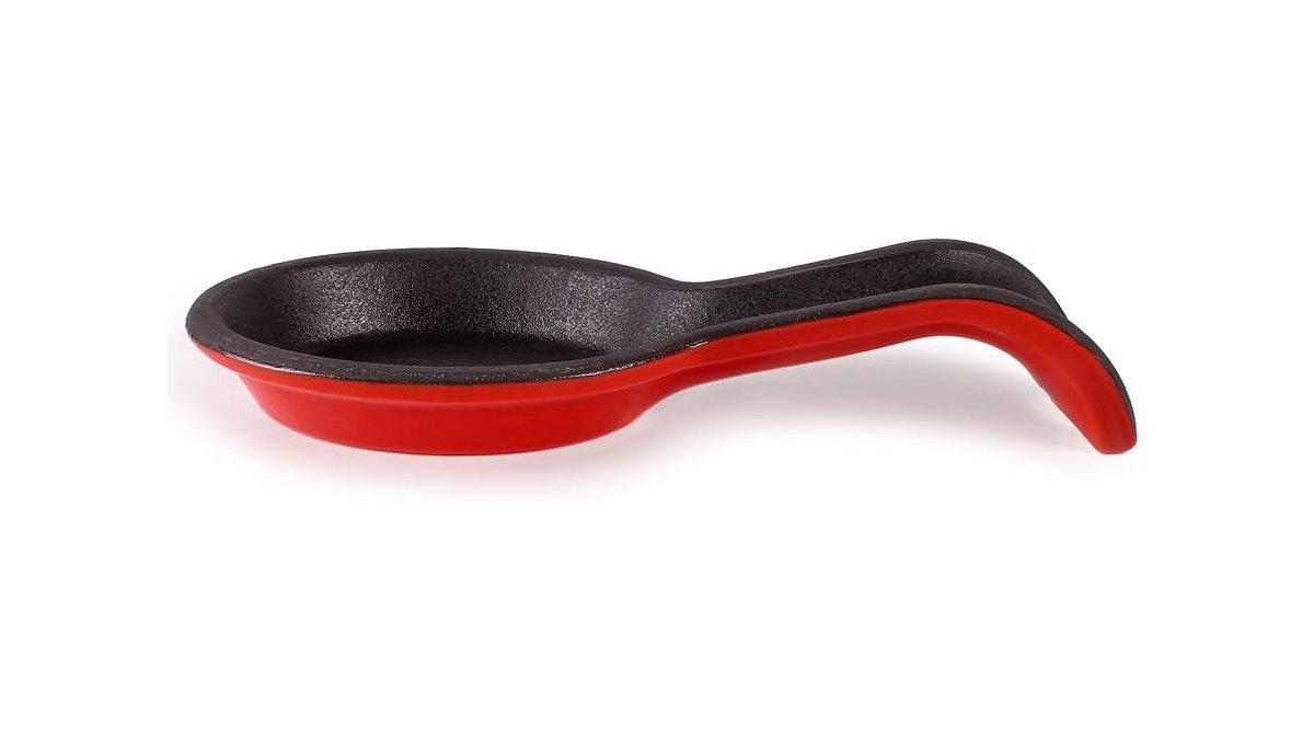 A heavy duty cast iron spoon rest sits on a marble kitchen countertop.