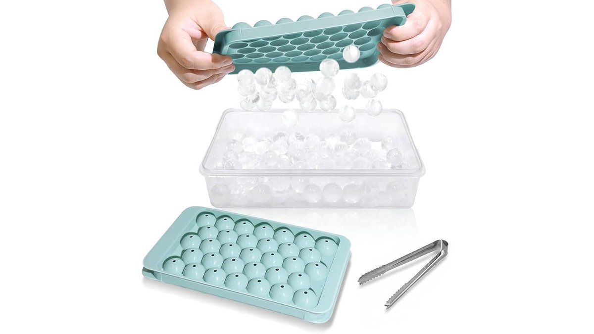 Mini ice cube tray beside a glass of iced coffee on a counter.