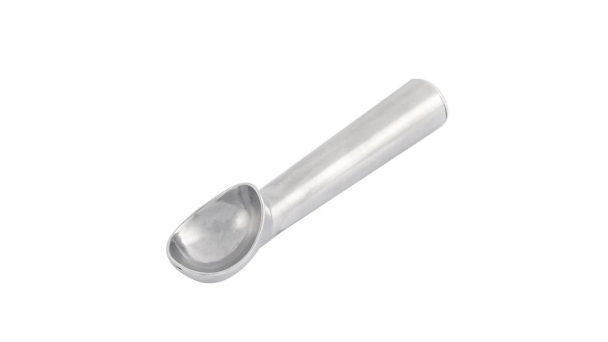 A professional nonstick ice cream spade spoon rests beside a pint of vanilla ice cream.