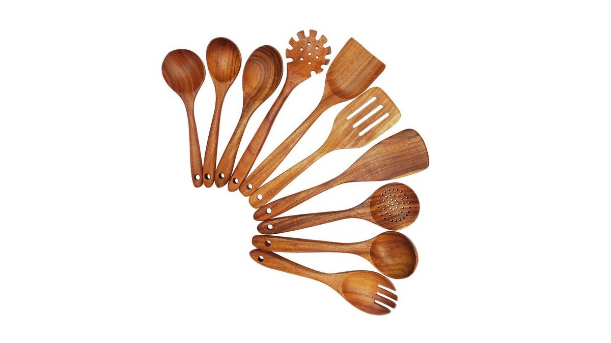 A set of teak wooden cooking utensils displayed neatly on a marble kitchen counter.