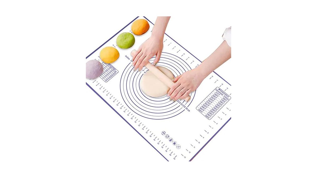 A silicone pastry mat with measurement guides sits on a marble kitchen counter.