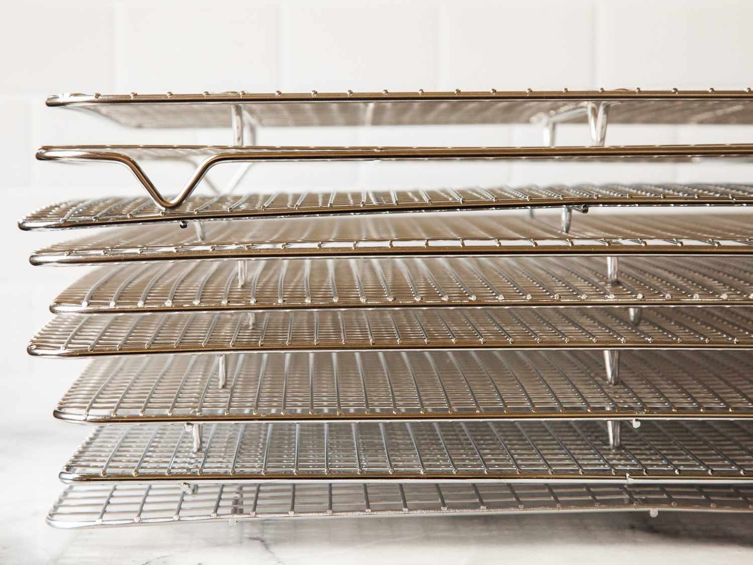 A stainless steel cooling rack with fresh cookies sits on a wooden counter.