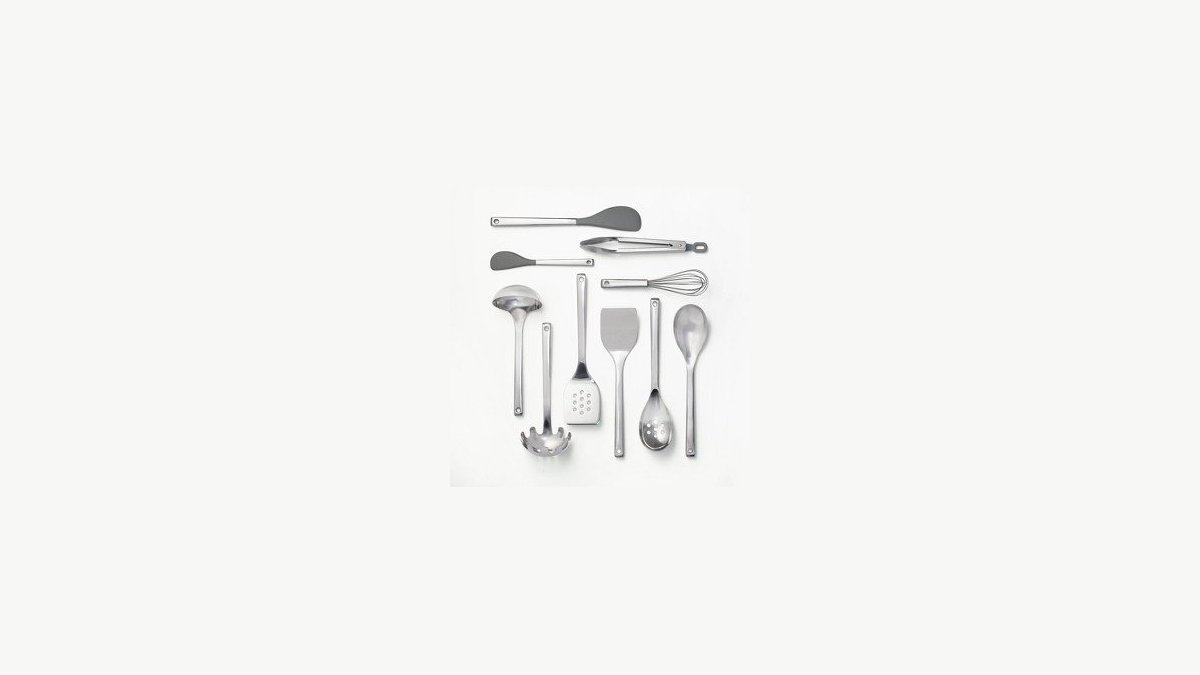 A stainless steel kitchen gadget set organized in a holder on a marble countertop.