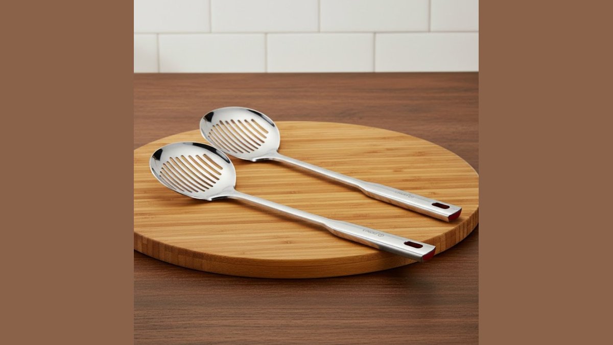 A stainless steel skimmer spoon resting on a skillet of bubbling frying oil.