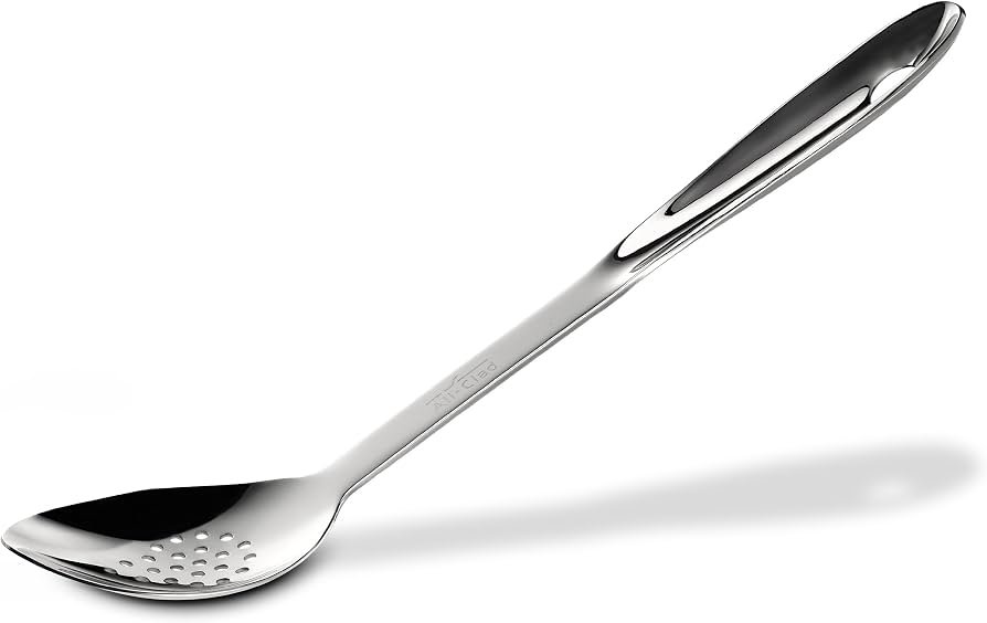 Stainless steel slotted spoon rests on a bowl of fresh vegetables.