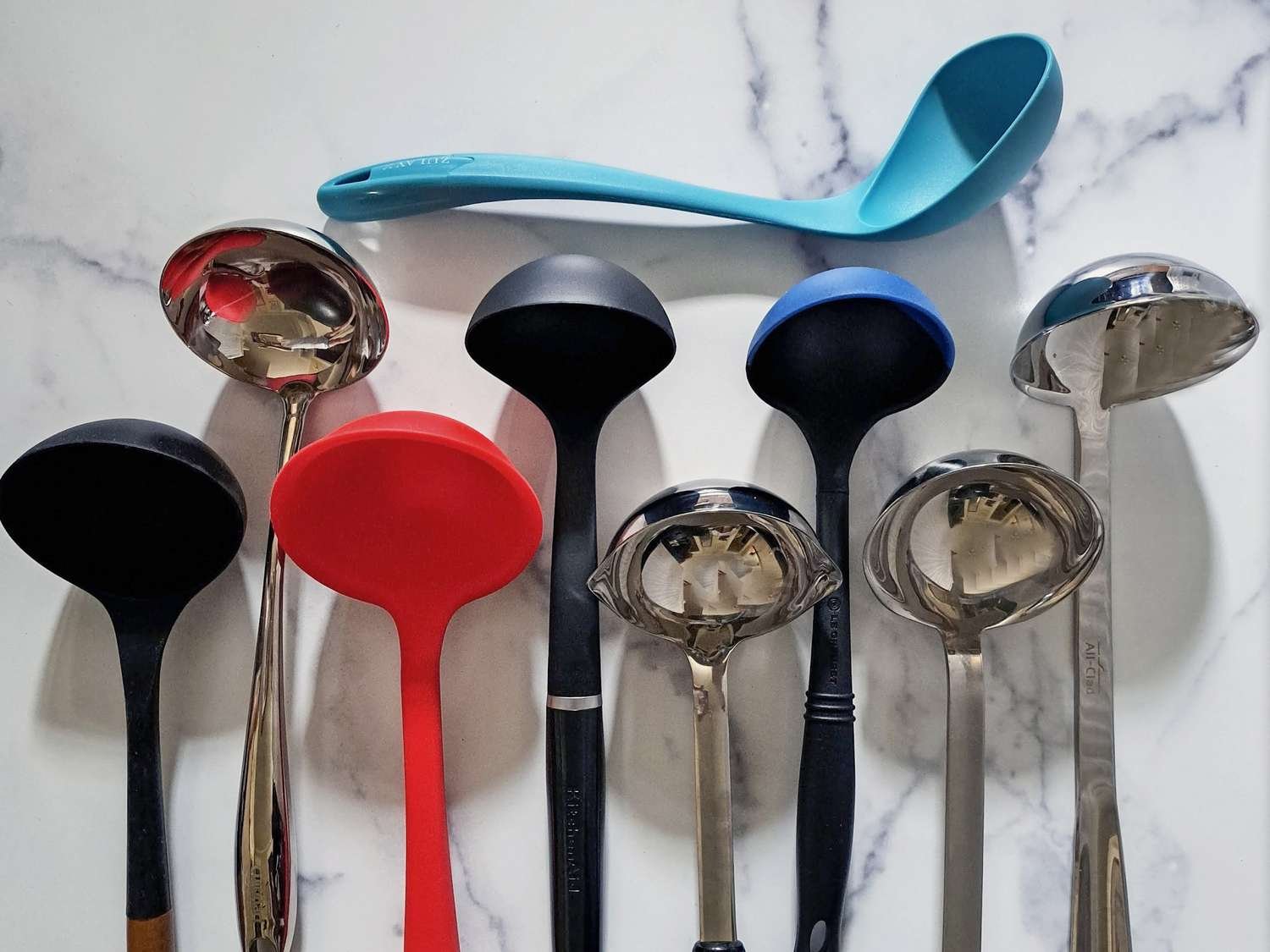 Stainless steel soup ladle resting on a white ceramic pot of golden broth.