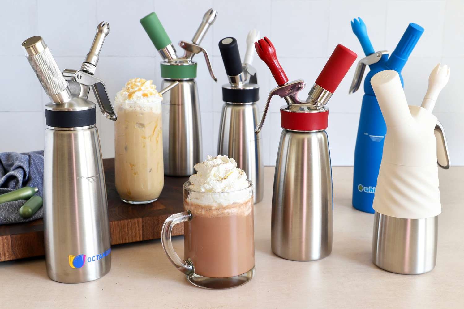 Stainless steel whipped cream dispenser on marble counter with fresh strawberries nearby