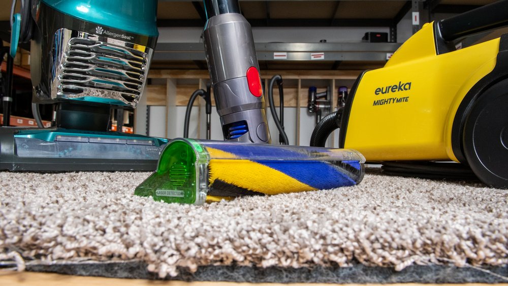 Upright vacuum cleaner on thick cream carpet in a bright living room